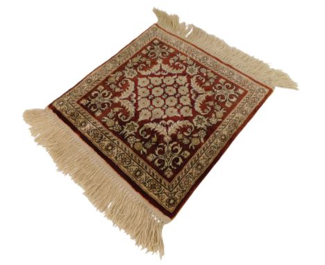 A Turkish silk mat or small carpet, red ground decorated with floral and scrolling motifs within one narrow, and one wide bor