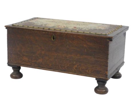 An early 20thC oak chest, the rectangular top inlaid with a floral tapestry panel enclosing vacant interior, on compressed tu