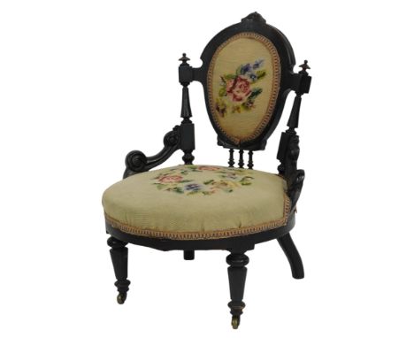 A Victorian ebonised nursing chair, with overstuffed seat and back, with tapestry upholstered overstuffed seat and back, on t