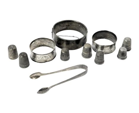 A group of small silverware, comprising a Victorian silver bangle, two silver napkin rings, seven silver thimbles, and a pair