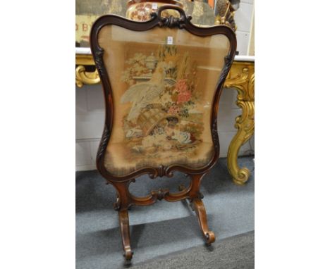 A Victorian rosewood framed fire screen with needlework panel.