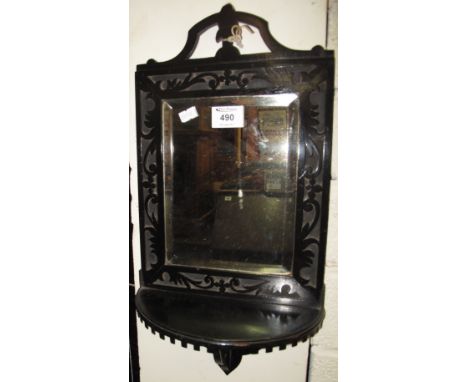 Small ebonised framed hall mirror with strap work, foliate decoration, bevel plate and demi lune shelf.(B.P. 24% incl. VAT)