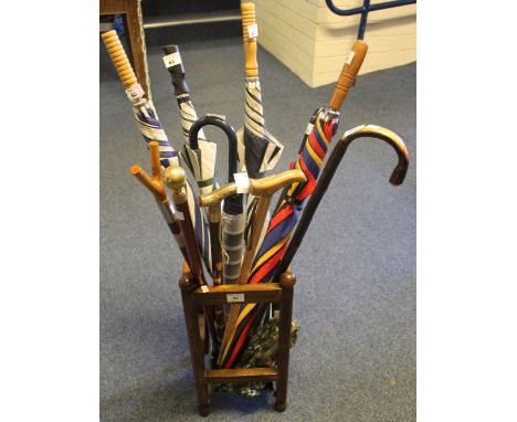 Oak walking stick stand containing a collection of assorted walking sticks, golfing and other type umbrellas, walking canes e
