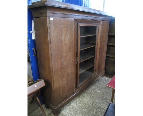 Large oak bookcase, having glazed centre door with fitted shelves, flanked by blind panel doors with fitted adjustable shelve