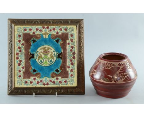 A Faience tile kettle stand decorated with birds within a crest and an Art Deco Vase with carved earthenware decoration of bi