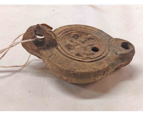 An old Roman style oil lamp with remains of old collection label and impressed mark to base