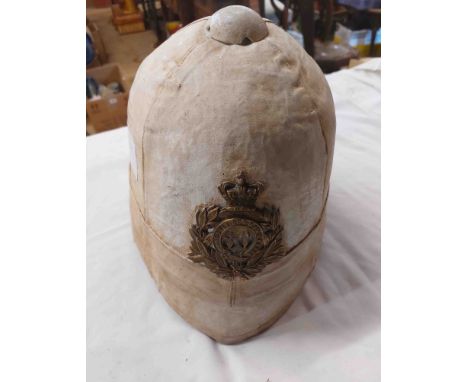 A British colonial regimental pith helmet with brass badge and canvas weather coat covering