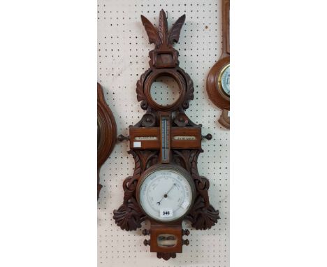 A late 19th Century ornate carved and pierced walnut Black Forest barometer with aperture for timepiece to top, central therm