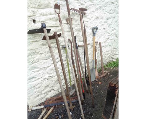 A quantity of assorted garden tools including billhooks, hoes, etc.