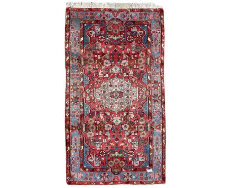 Persian Hamadan red ground rug, central medallion within a field of trailing branches and stylised flower heads with urns, th