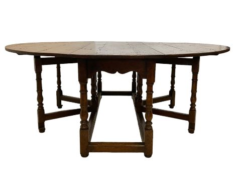 18th century design country oak dining table, the oval drop-leaf top over a shaped apron, raised on turned supports with twin
