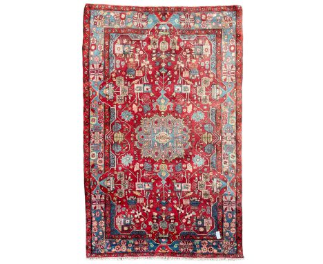 Persian Hamadan red ground rug, central medallion within a field of trailing branches and stylised flower heads with urns, th