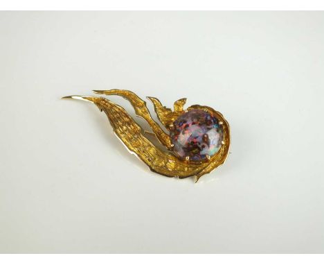 A boulder opal brooch, designed as a round polished cabochon boulder opal claw set to textured yellow metal stylised wave mou