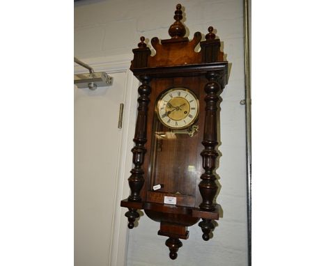 Walnut and stained wood Vienna wall clock, urn pediment, glazed door flanked by spindles, spring driven movement, 98cm.