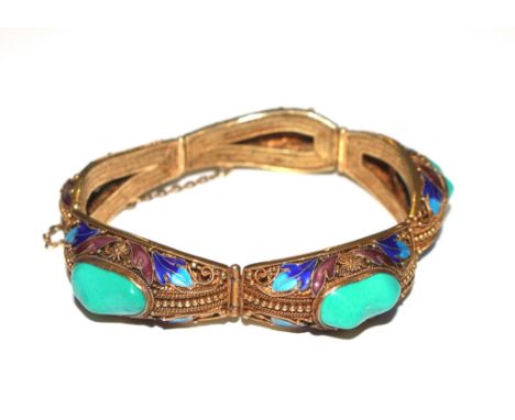 An Oriental stone set gilded bangle with enamel decoration