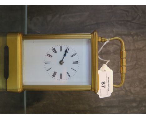 A gilt brass carriage clock striking the half hour, white enamel dial with Roman numerals, 17cm high