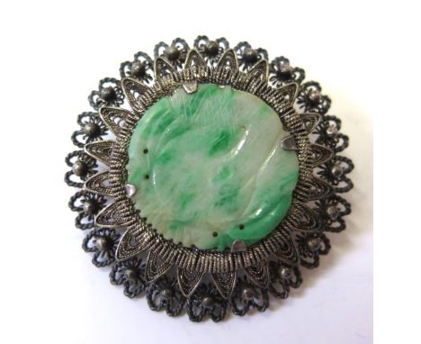 A silver brooch set with a carved jade centre