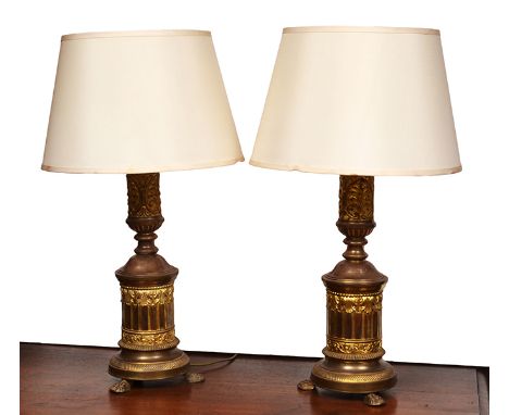 A PAIR OF FRENCH EMBOSSED BRASS COLUMNAR LAMP BASES
each with a foliate embossed stem above a fluted lower section, lion's pa