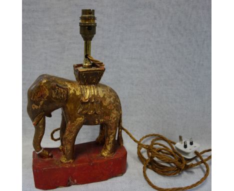 A CARVED GILTWOOD AND RED LACQUERED ELEPHANT TABLE LAMP, 24cm high (plus fitting)