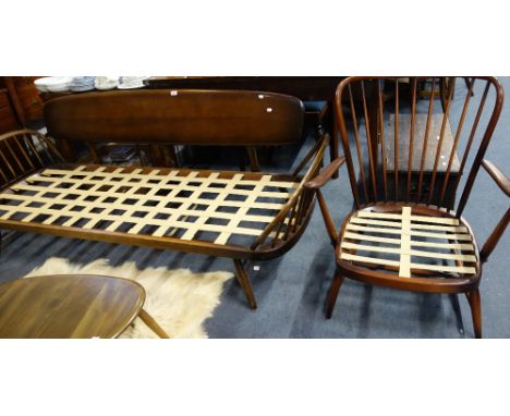 ERCOL: A dark stained three seater studio couch with spindle ends and panelled back, 215cm long and a similar armchair (no cu