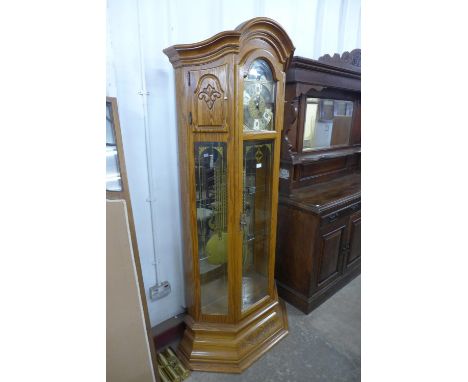 A German carved oak triple weight longcase clock, with brass moonphase rolling dial 