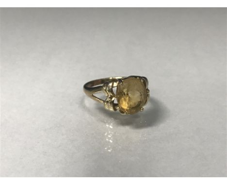 YELLOW GEM SET RING the oval yellow stone on bifurcated shoulders with overlaid decoration, in nine carat gold, size N, 4.5g