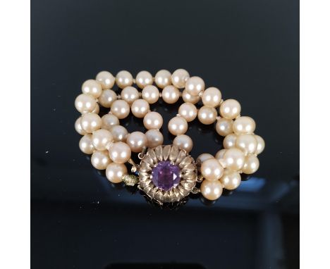 A triple strand simulated pearl bracelet set with flower design 9ct gold clasp with amethyst centre