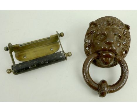 A cast iron lion mask door knocker and a brass toilet roll holder. 