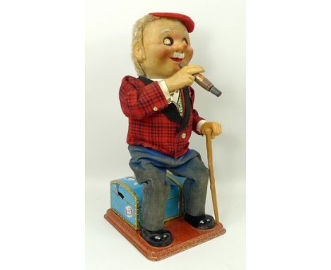 A Japanese, Namura,  'Macgregor' mechanical smoking figure, modelled seated on a cabin trunk, 31cm high. 