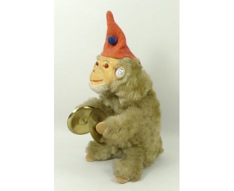 A West German mechanical monkey wearing a pointed hat and clashing cymbals, with a winder to the back, 22cm high. 