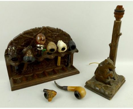 A Black Forest pipe rack, with eight carved wood and meerschaum pipes, 31cm wide, and a Black Forest table lamp carved with a