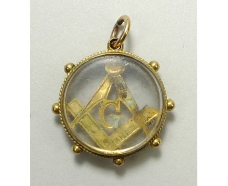 A 9ct gold Masonic charm of circular form set centrally with a set square and compass, glass front and back.