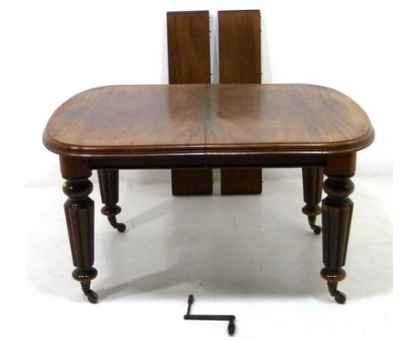 A Victorian mahogany dining table, with two extra leaves, raised on lobe carved legs and ceramic castors, with winder, 134 by