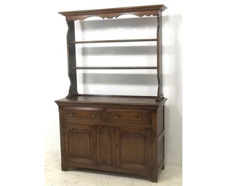 An oak dresser with a two shelf open Delft rack, the base with two drawers over two panelled cupboard doors below, 130 by 48 