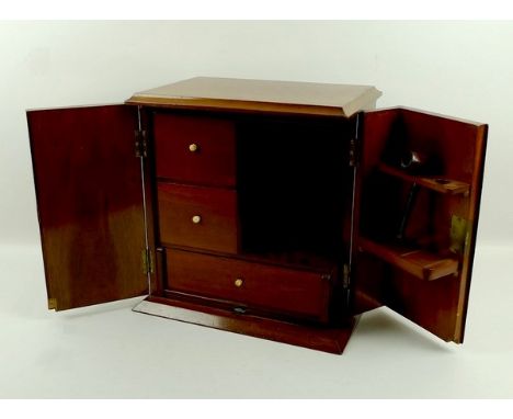 A Victorian mahogany smoker's cabinet , the two doors opening to reveal drawers and a pipe rack, raised on a plinth base, 31.