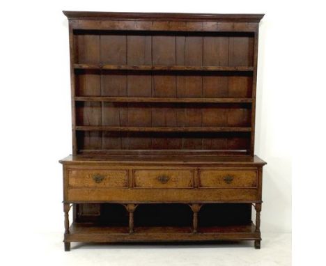 A George III oak dresser and rack, the rack having three graduated plate shelves, the base with three frieze drawers with coc