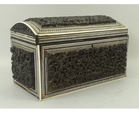 An Indian ebony and ivory tea caddy, 19th century, of domed, twin division form with panels carved with buildings, animals, b