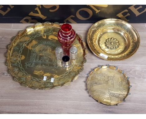 TWO CIRCULAR BRASS TRAYS AND A BRASS WALL PLAQUE ALL NICELY ETCHED TOGETHER WITH GLASS AND SILVER PLATED BOTTLES PLUS RUBY GL