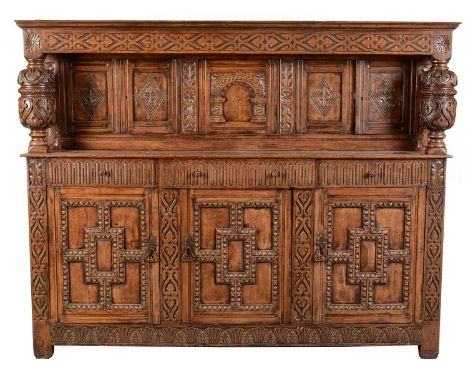 A large and impressive 17th Century style carved oak court cupboard, with blind fret frieze above five recessed lozenge and a