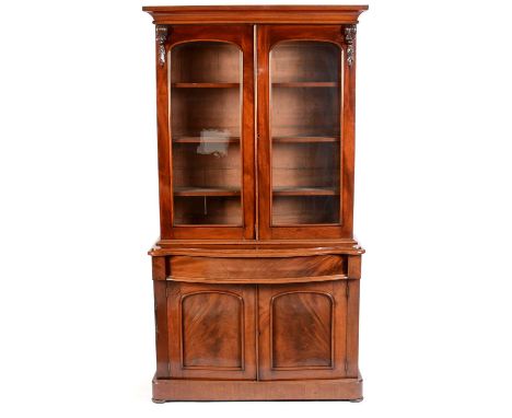 A Victorian mahogany serpentine fronted bookcase, the top with cavetto cornice above a pair of arched glazed doors enclosing 