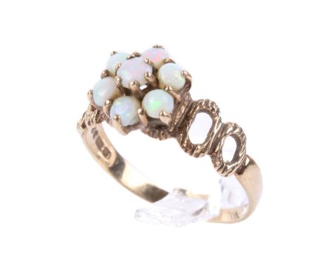 A 9ct gold opal cluster ring. The seven small opals in flower form flanked by pierced shoulders, Sheffield hallmarks, 375. Si
