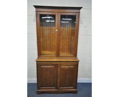 AN EARLY 20TH CENTURY OAK BOOKCASE, with a double glazed top, over fielded panel doors, width 107cm x depth 44cm x height 215