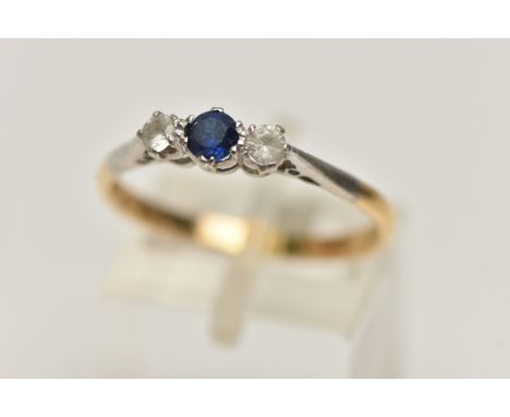 A YELLOW METAL THREE STONE RING, set with a central circular cut blue sapphire, flanked with circular cut colourless stones a