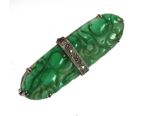 GREEN JADE OVAL PLAQUE BROOCH, carved with fruit and flowers and mounted on a white gold coloured metal frame with a band pas