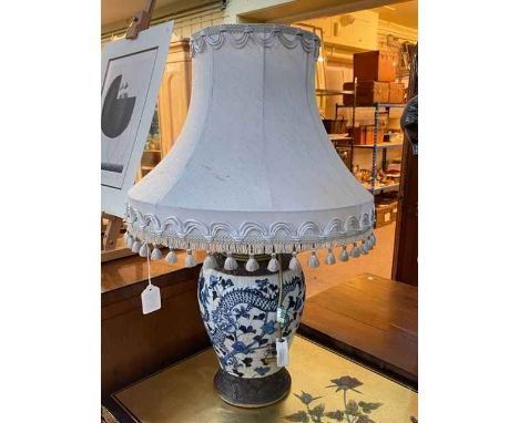 Chinese blue and white pottery table lamp decorated with dragon and floral scene with silk shade.