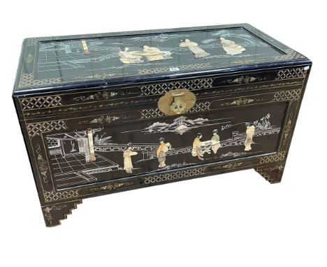 Black lacquered camphor trunk with applied figure decoration, 60cm by 103cm by 52cm.