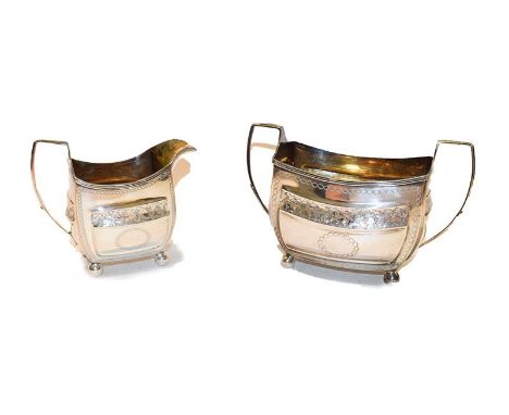 A George III silver sucrier and cream jug (makers mark indistinct), engraved with flowers and loop borders and raised on ball