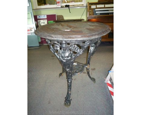 A circular Tavern Table the dark stained hardwood top 24" diameter supported on a cast iron base, each of the three legs depi