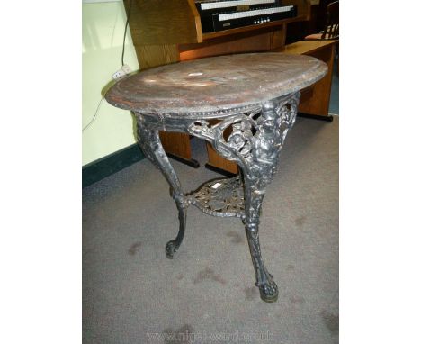 A circular Tavern Table the dark stained hardwood top 24" diameter supported on a cast iron base, each of the three legs depi