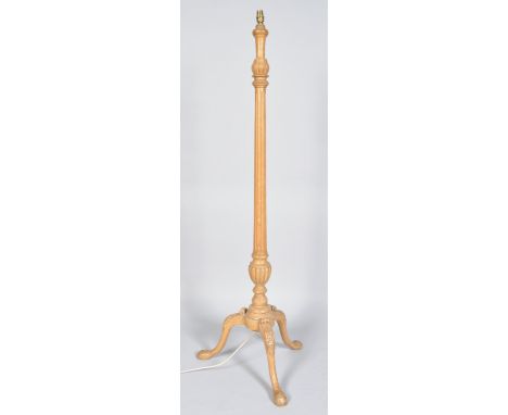 A beech wood tripod standard lamp, of column form, raised on an urn on cabriole legs with carved knees and pad feet, 151cm hi